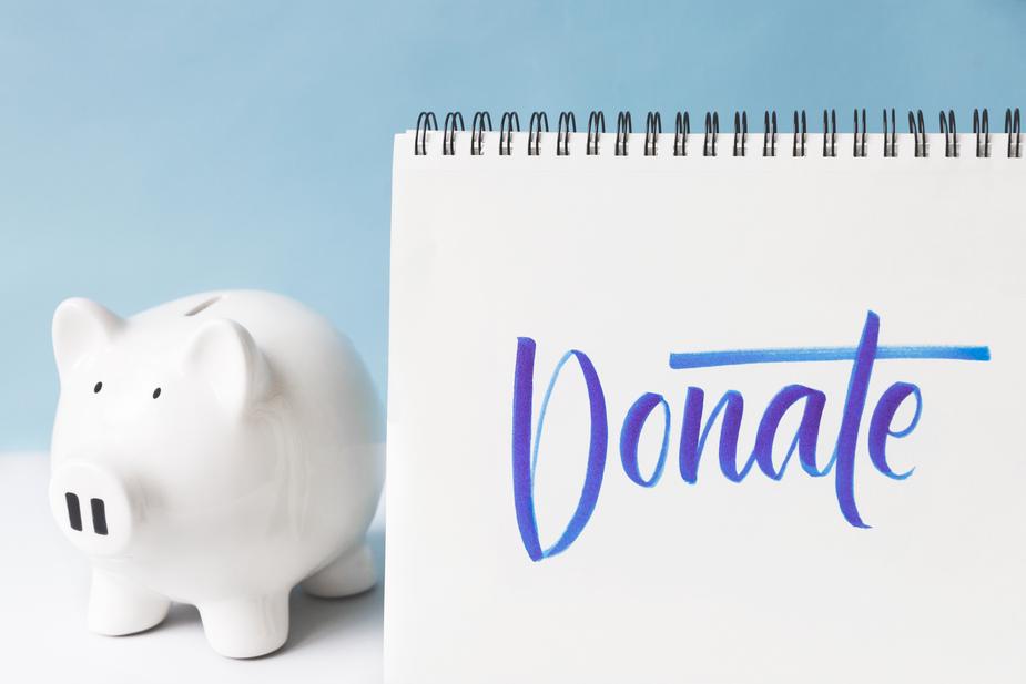 Piggy bank next to notebook with the text donate